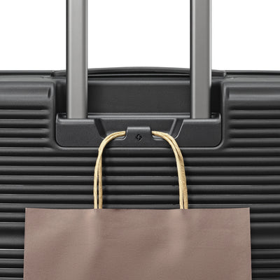 Samsonite Paralux Global black carry-on hardside spinner, add-a-bag hook holding a shopping bag
