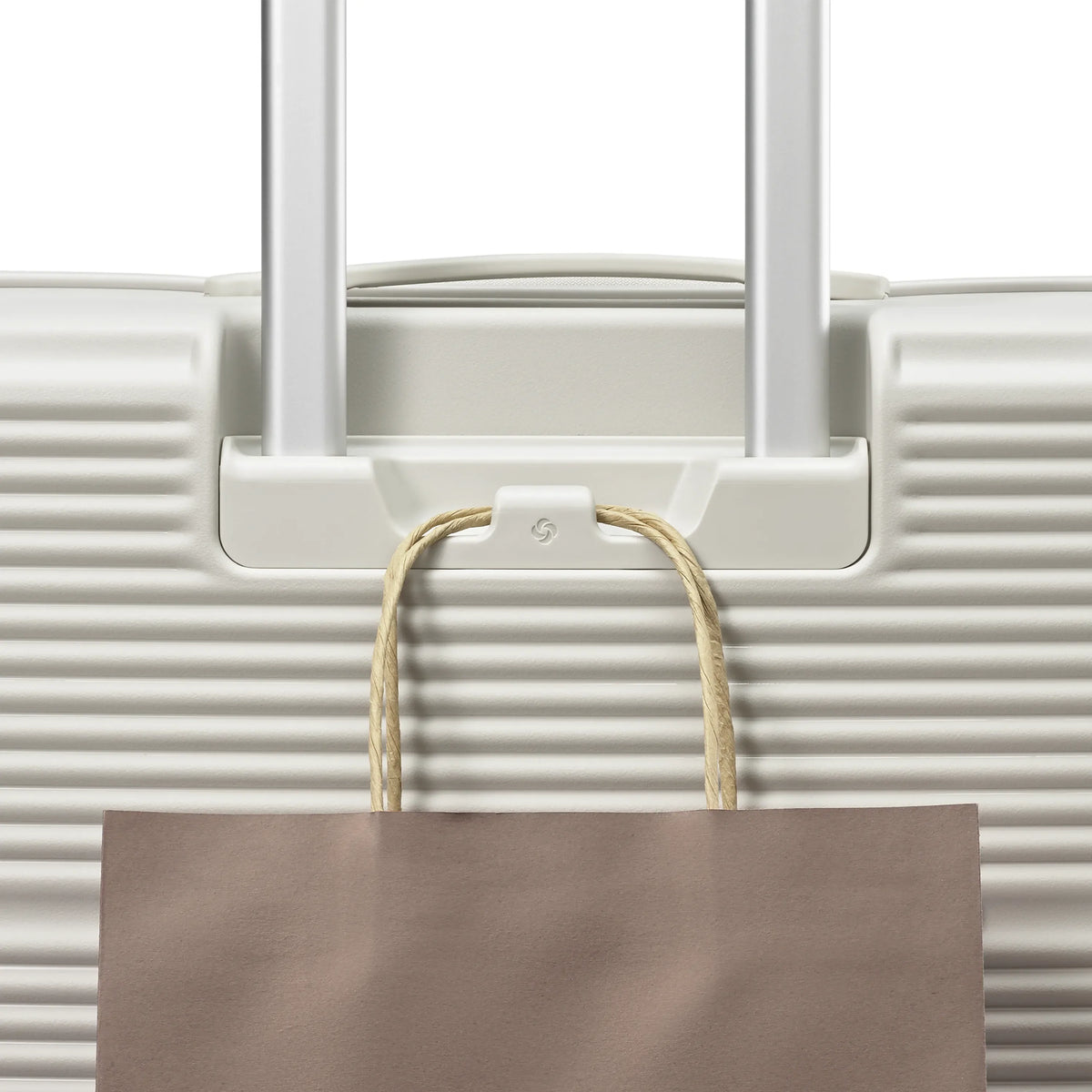 Samsonite Paralux stone grey large checked hardside spinner, add-a-bag hook holding a shopping bag